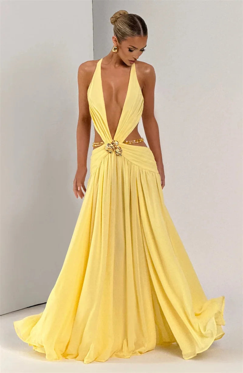 Woman wearing a yellow evening gown with a plunging neckline and gold belt on a plain background