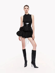 Back view of a black sleeveless turtleneck dress with a glossy bodice and ruffled mini skirt.