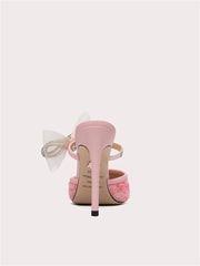 Pink high-heeled shoe with a bow on a white background
