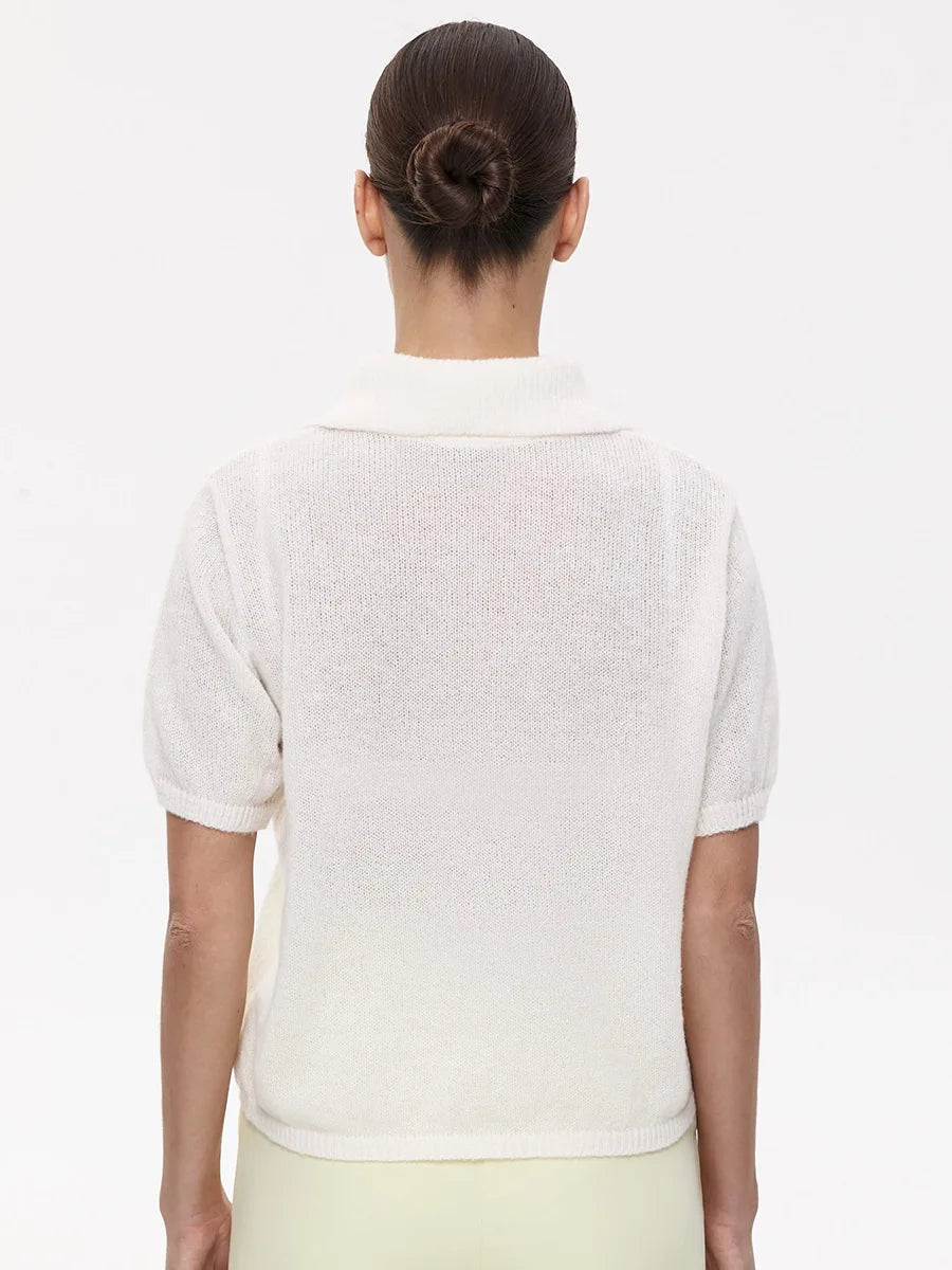 Person wearing a white short-sleeve cardigan on a plain background