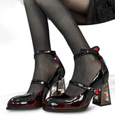 Black patent high-heeled shoes with red accents worn by a person.