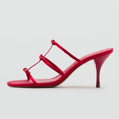 Side view of red stiletto heels with bow straps.