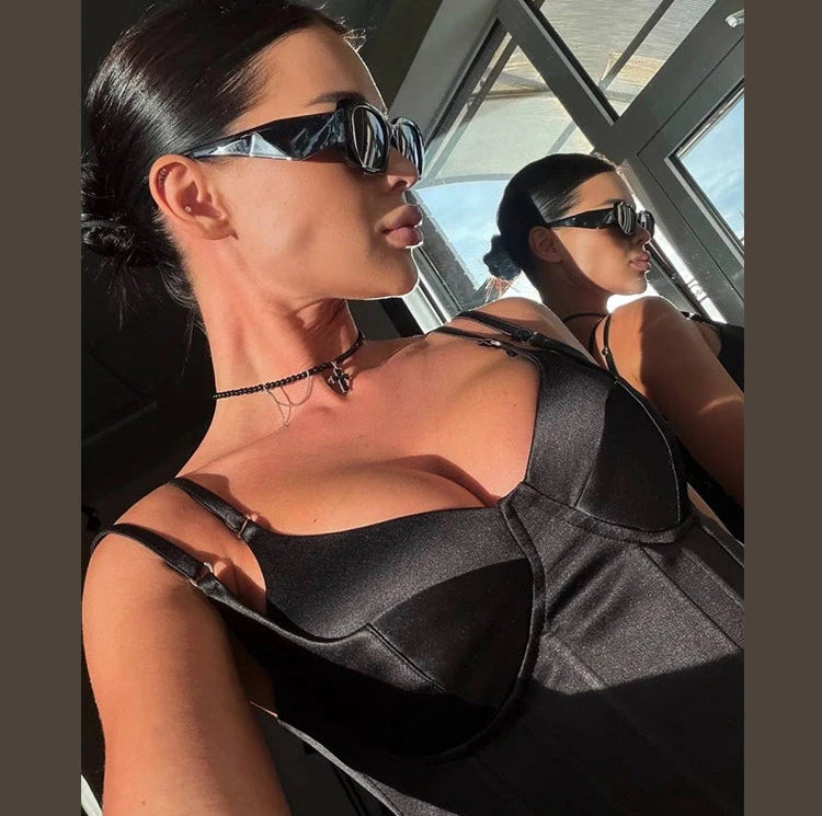 Woman wearing a black outfit and sunglasses inside a vehicle.