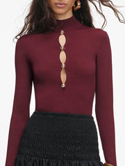 Maroon long-sleeve top with decorative cutouts on a white background