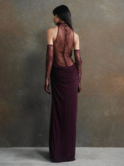 Woman wearing a dark burgundy evening gown with sheer lace detailing against a gray background
