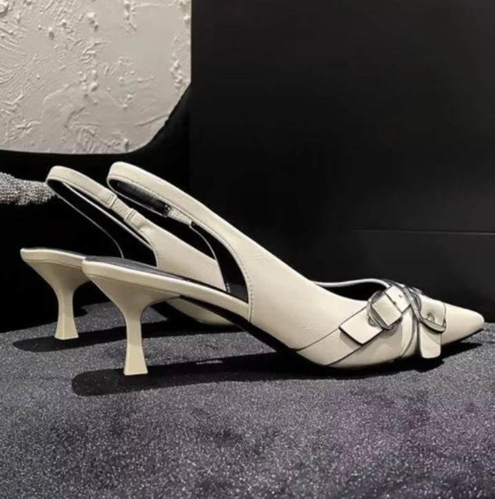 Pair of beige high-heeled shoes with a buckle on a textured surface.