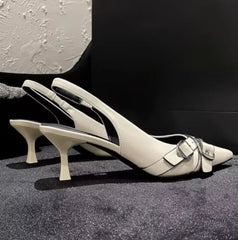 Pair of beige high-heeled shoes with a buckle on a textured surface.