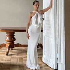 Woman in white halter backless dress standing in elegant interior