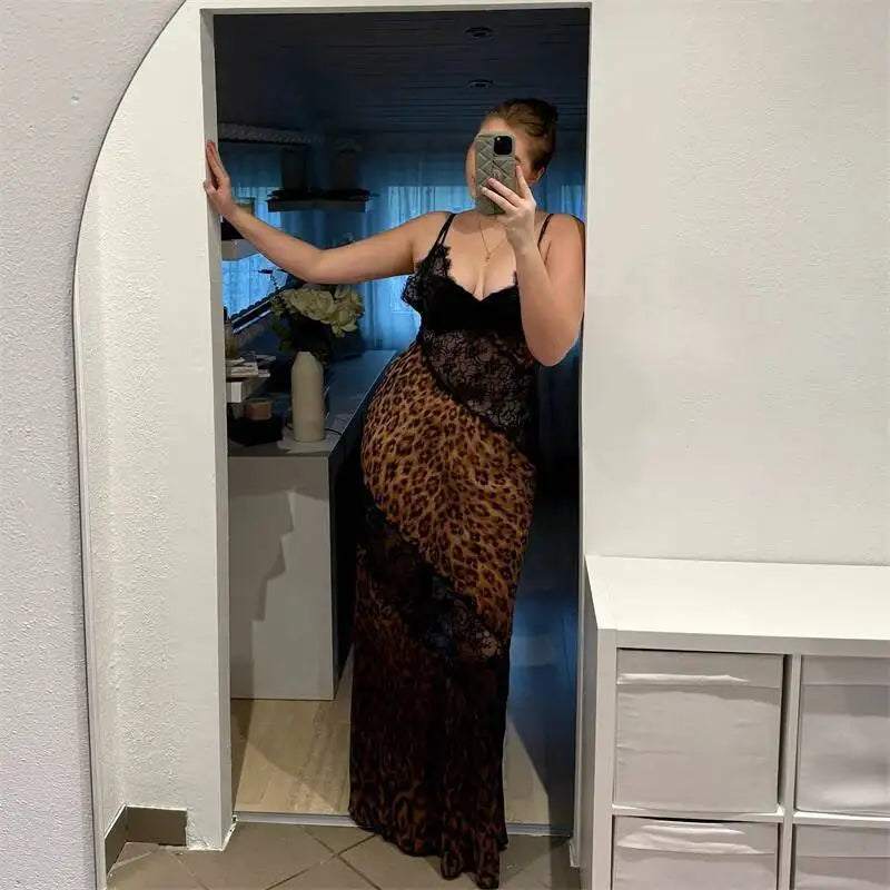 Person taking a mirror selfie wearing a black and leopard print dress in a room.