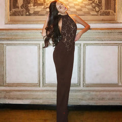 Woman in a brown lace dress standing in an elegant room with decorative wall art.