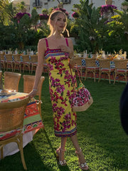 Woman in a floral dress standing outdoors with tables and chairs in the background