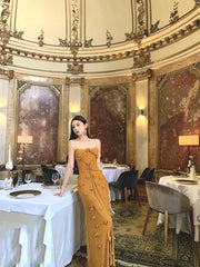 Woman in a yellow dress standing in an ornate dining room with tables and chairs.