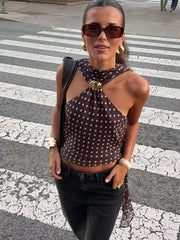 Woman in a polka dot top and sunglasses standing on a crosswalk