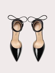 Black pointed-toe high heels with thin straps on a light gray background