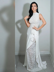 Woman in a white evening gown posing against a plain background