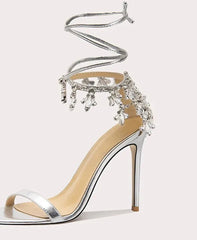 Silver high-heeled shoe with embellishments on a white background