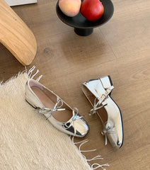 Pair of metallic shoes on a wooden floor with a rug and fruit bowl in the background.