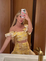 Woman taking a mirror selfie wearing a yellow off-shoulder outfit.