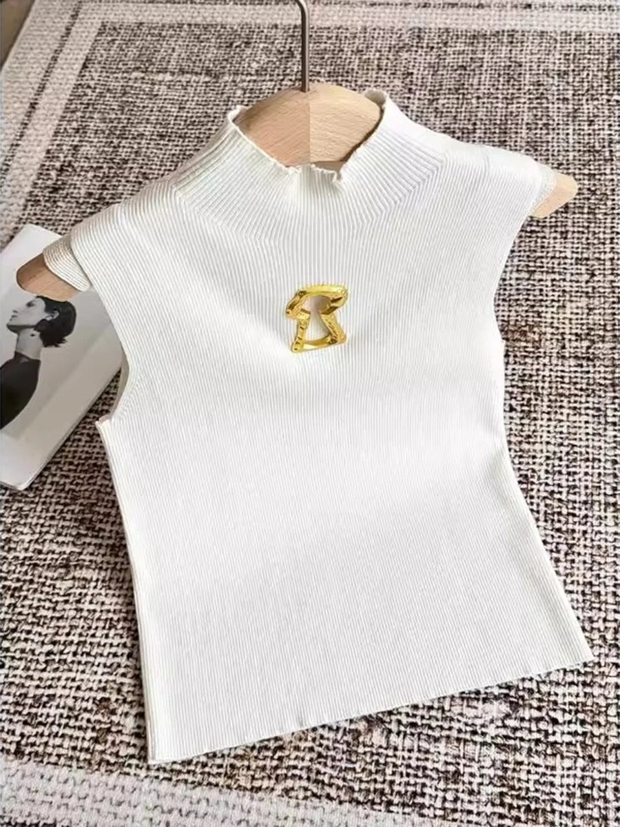 White top with a gold brooch on a textured surface