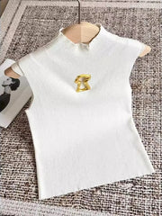 White top with a gold brooch on a textured surface