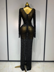 Black beaded evening gown on a mannequin against a white wall.