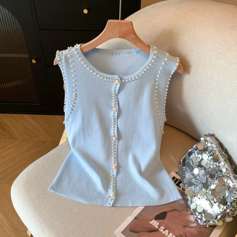 Light blue sleeveless top with pearl embellishments on a hanger.