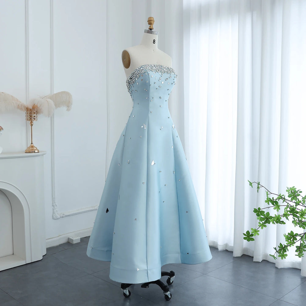 Light blue evening gown on a mannequin against a white curtain background