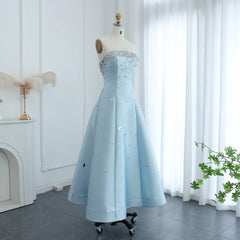 Light blue evening gown on a mannequin against a white curtain background
