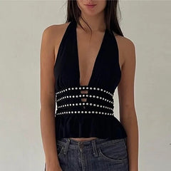 Black halter top with pearl embellishments worn by a person on a plain background