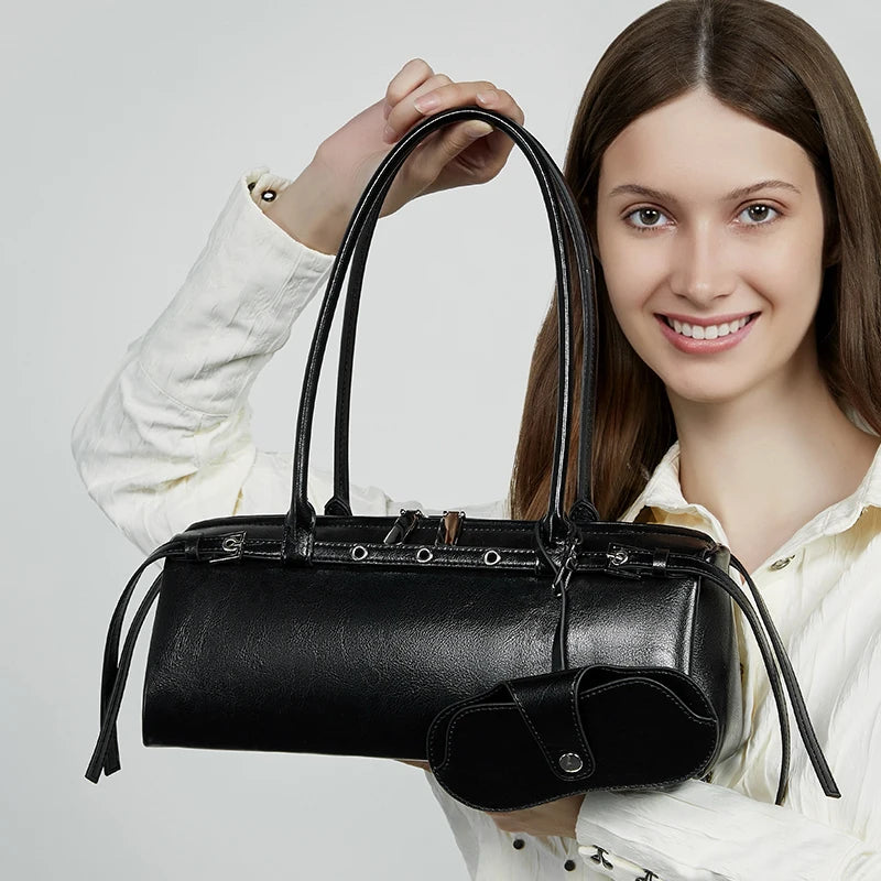 Woman holding a black handbag against a plain background