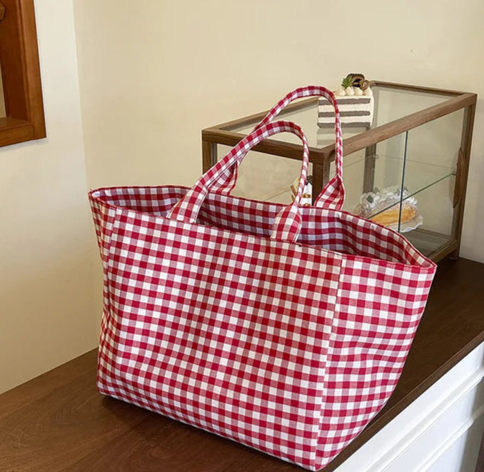 Red and white checkered tote bag on a wooden surface with a neutral background