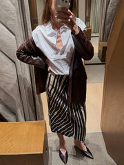 Woman wearing a white shirt and brown jacket with a zebra print straight midi skirt
