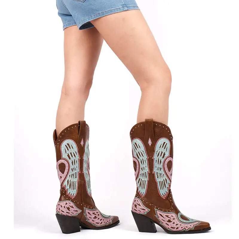 Brown cowboy boots with decorative patterns worn by a person on a white background