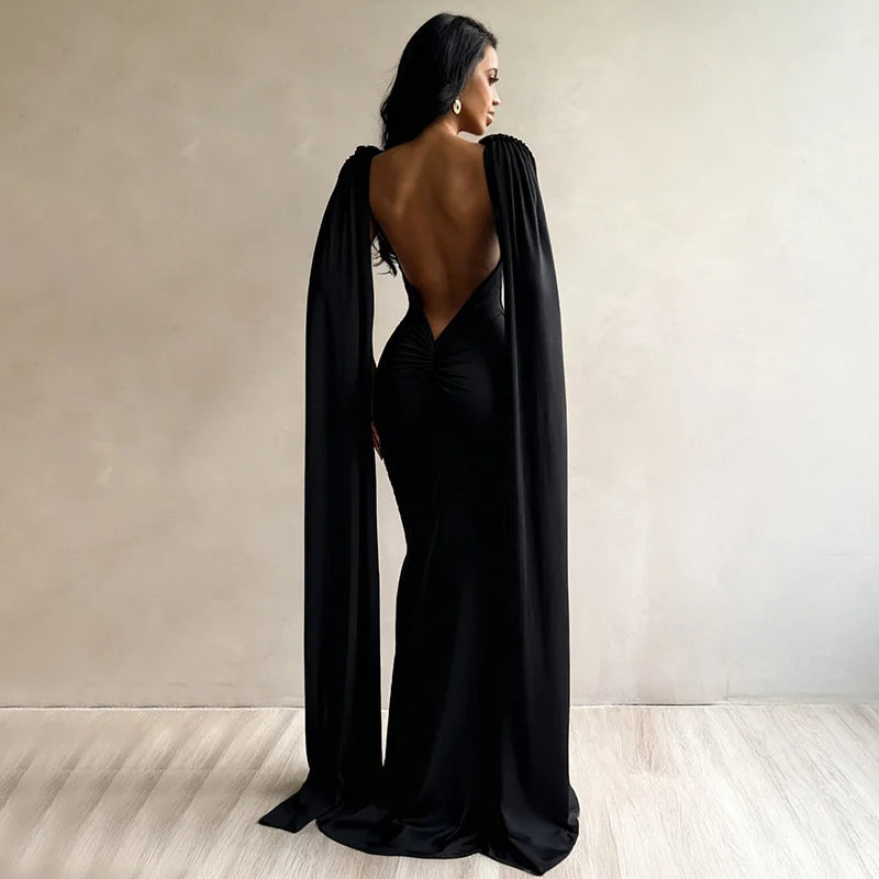 Woman wearing a black evening gown with a cape in a minimalistic setting