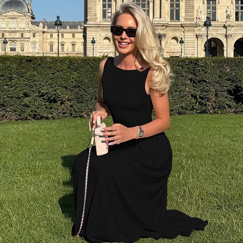 Woman in a black dress sitting on grass with a historic building in the background