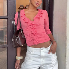Pink ruffle V-neck cropped top with ruched bodice and three-quarter sleeves.