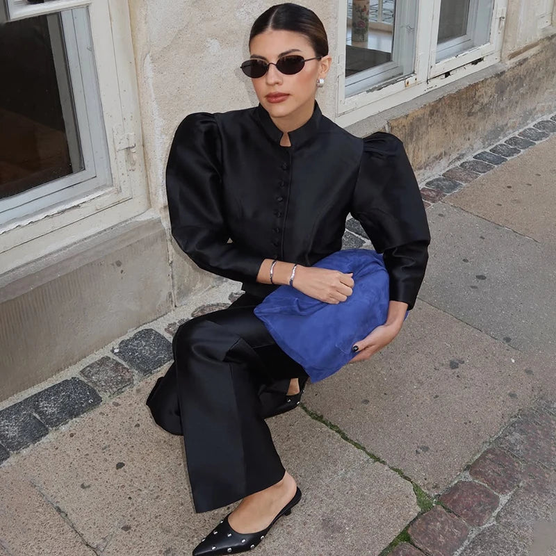 Person in black outfit holding a blue bag on a street.