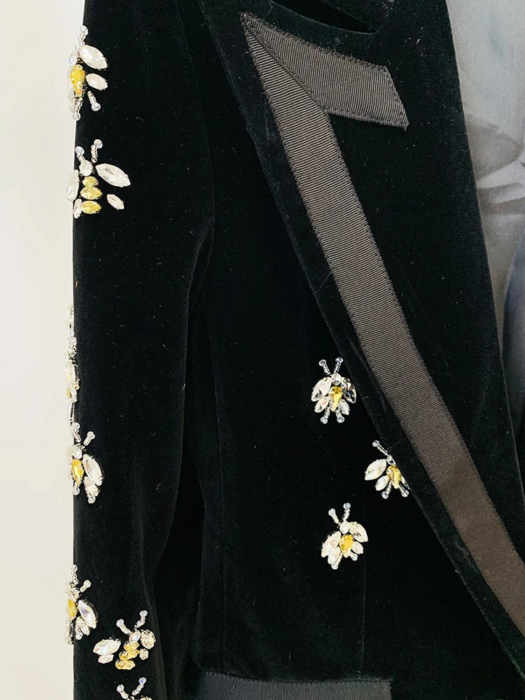 Close-up detail of beaded bee embellishments and ribbon lapel on a black velvet blazer.