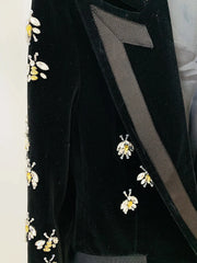 Close-up detail of beaded bee embellishments and ribbon lapel on a black velvet blazer.