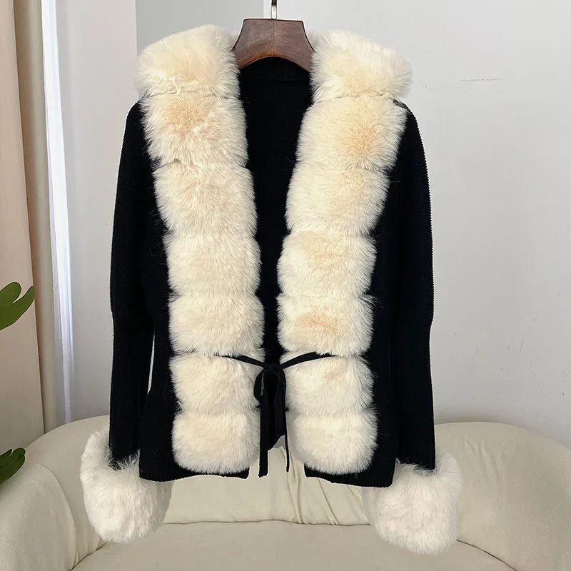 Black coat with white fur trim on a hanger against a neutral background