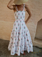 Woman wearing a white floral dress against a wooden wall.