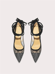 Pair of black lace-up high-heeled shoes on a light gray background