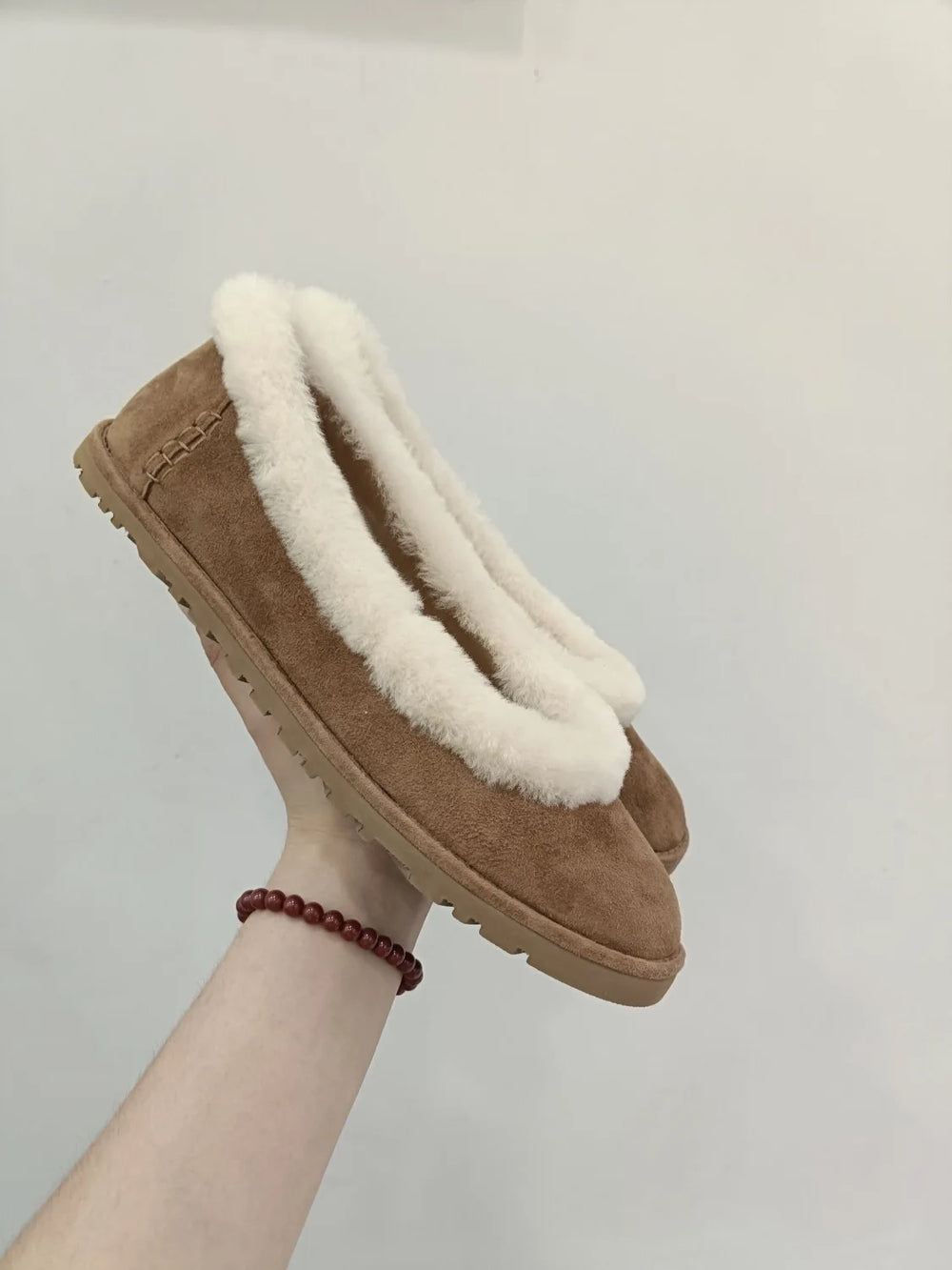 Side view of fleece lined slip on loafers held in hand