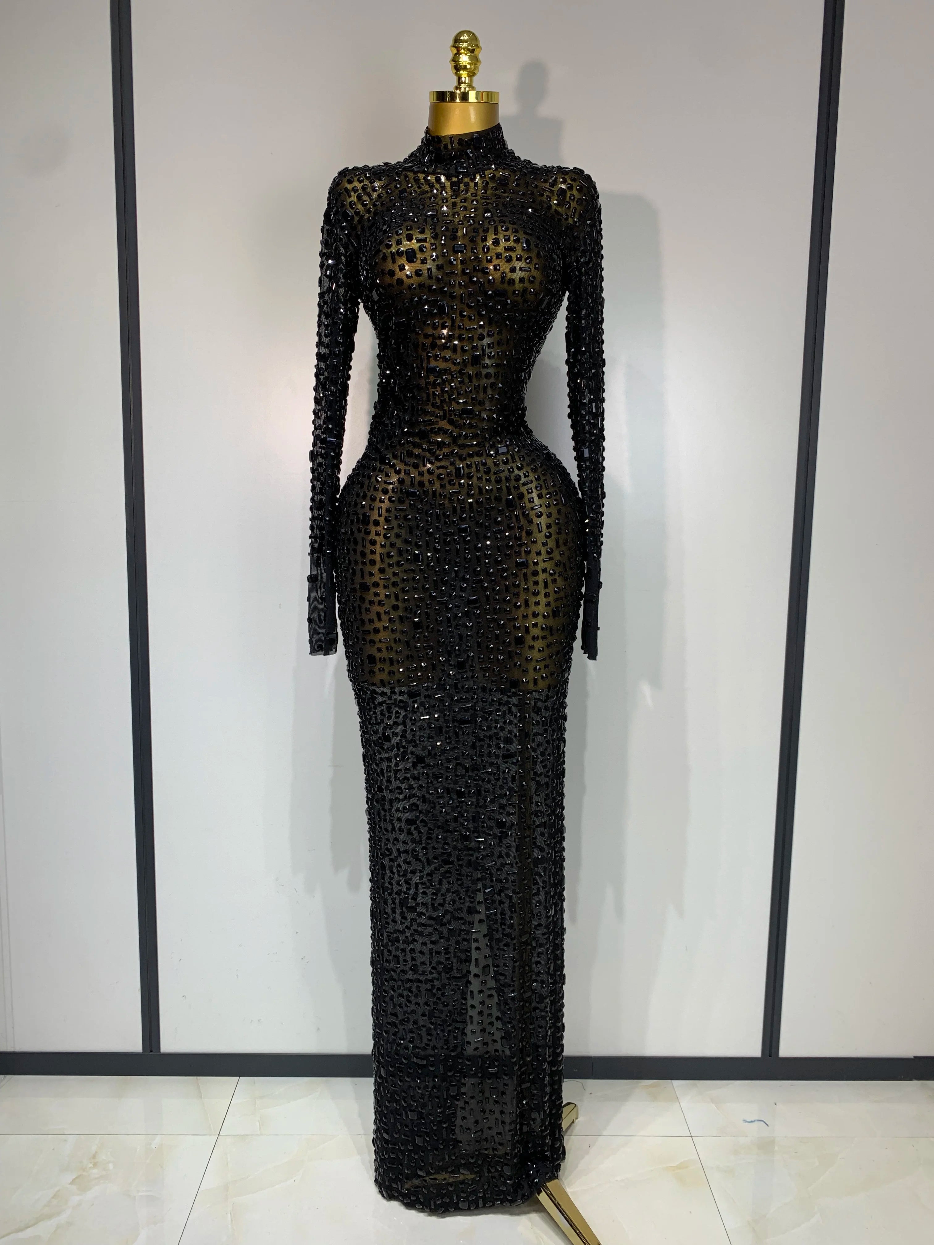 Black beaded evening gown on a mannequin against a plain background