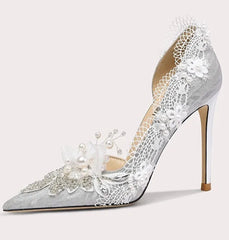 Silver high-heeled shoe with lace and pearl details on a white background