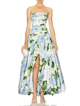 A woman wearing a strapless floral dress with a slit