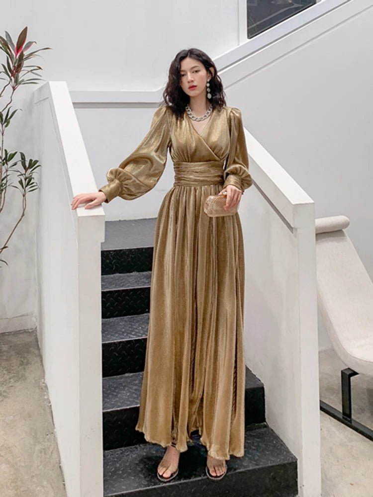Woman in a gold dress standing on a staircase in an indoor setting