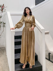 Woman in a gold dress standing on a staircase in an indoor setting