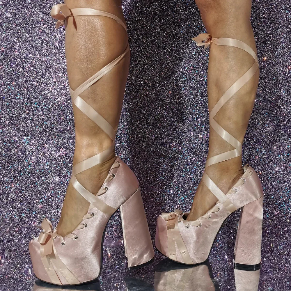 Beige high-heeled platform shoes with criss-cross straps on a glittery purple background