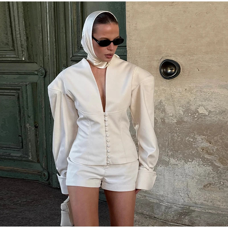 Person wearing a white outfit with a hood in front of a textured wall.